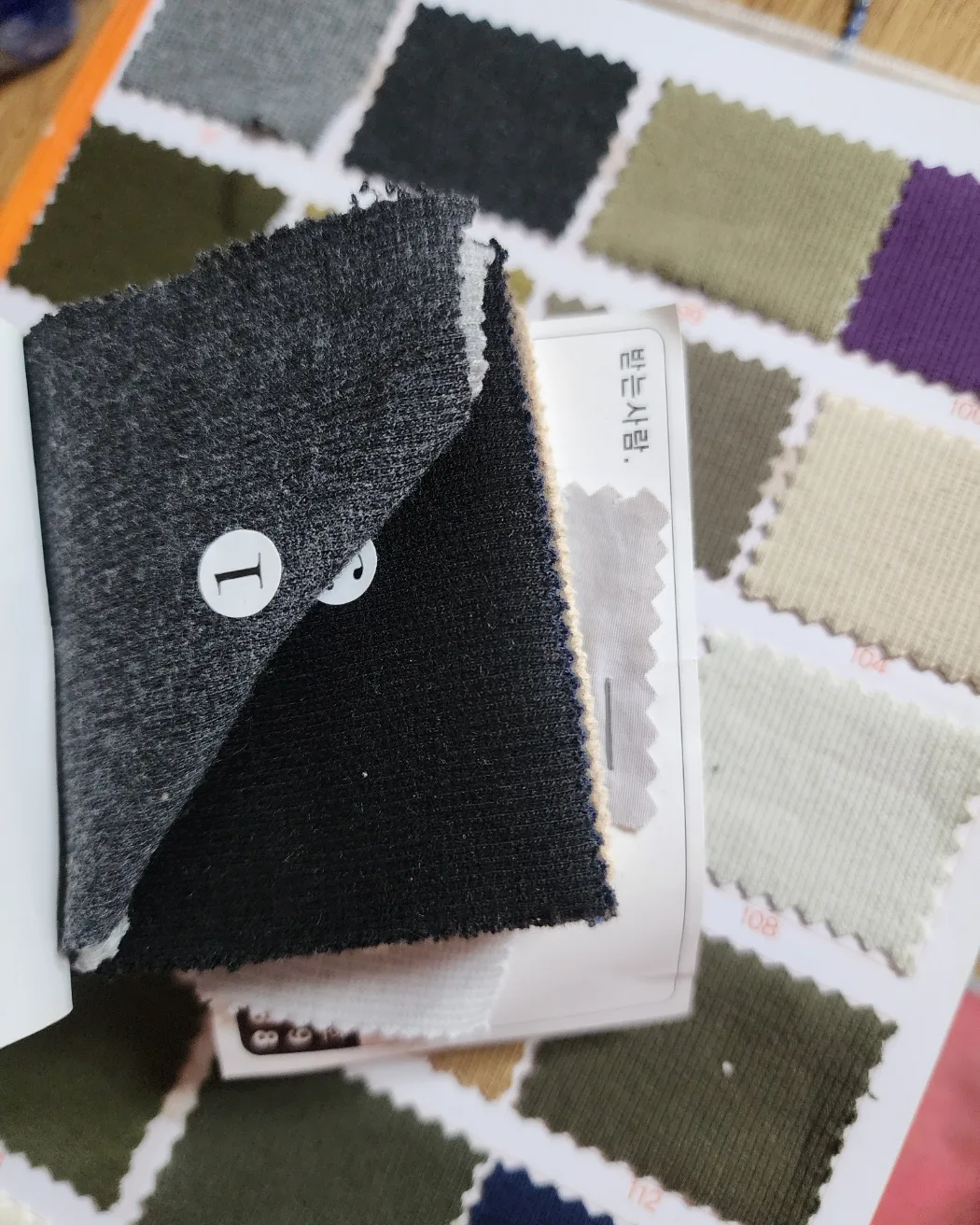 A fabric swatch card with knit samples in several colors