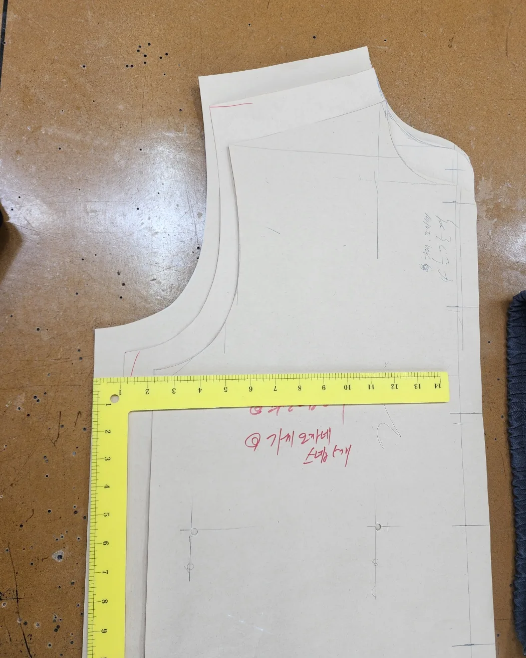 A paper pattern with corrections written in red pen and an L-square ruler laid on top